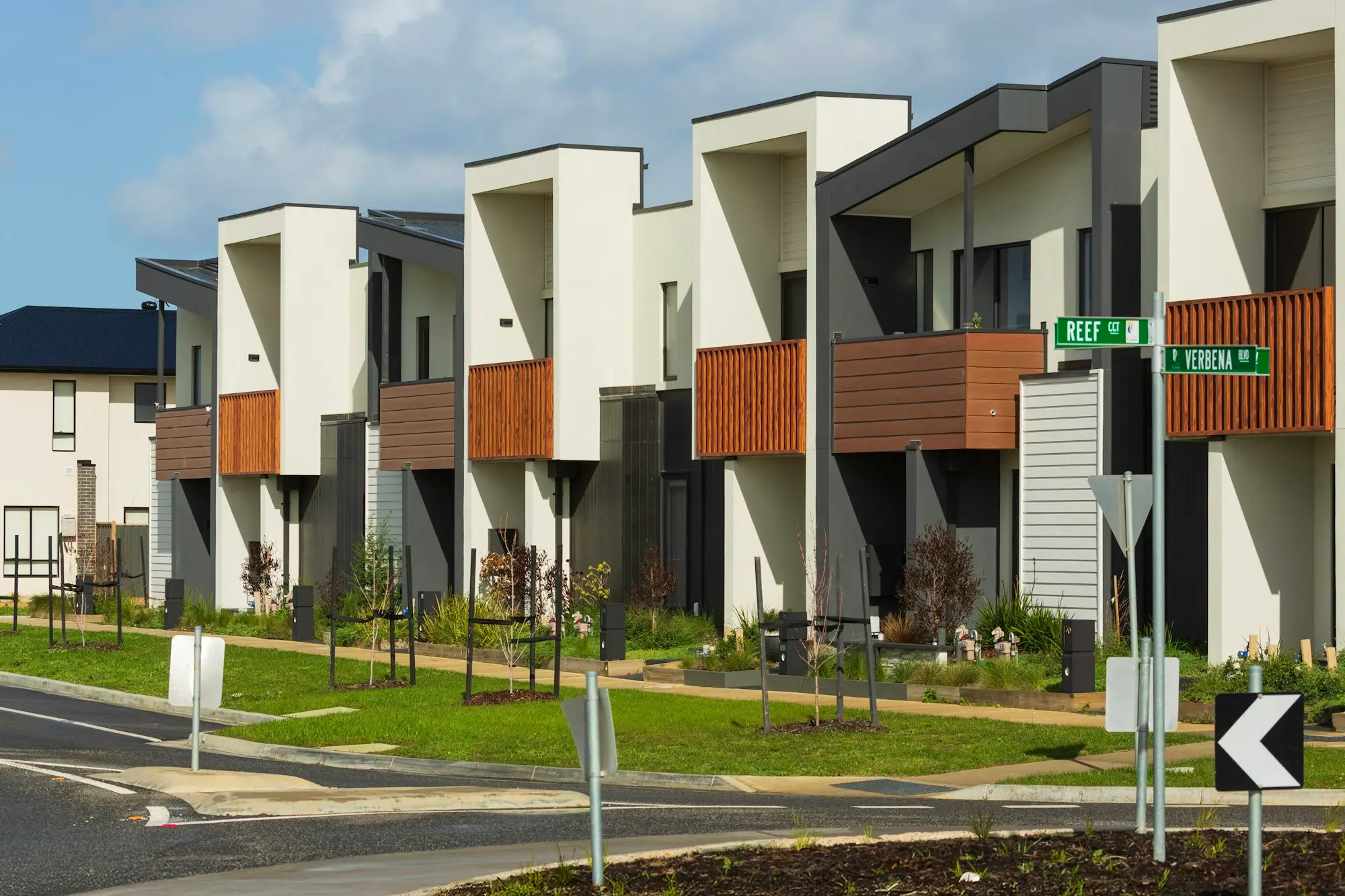 Row of newly completed modern townhouses with geometric facades on a suburban street