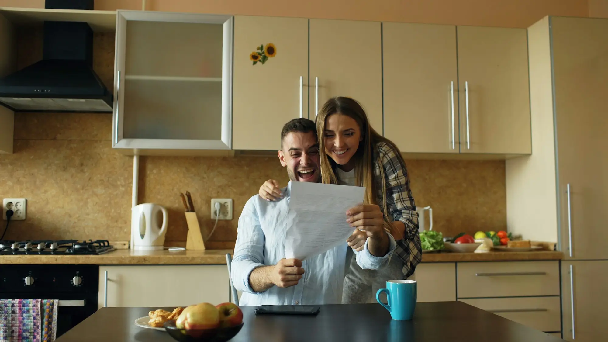 Smiling couple reading through a letter together at their kitchen table at home