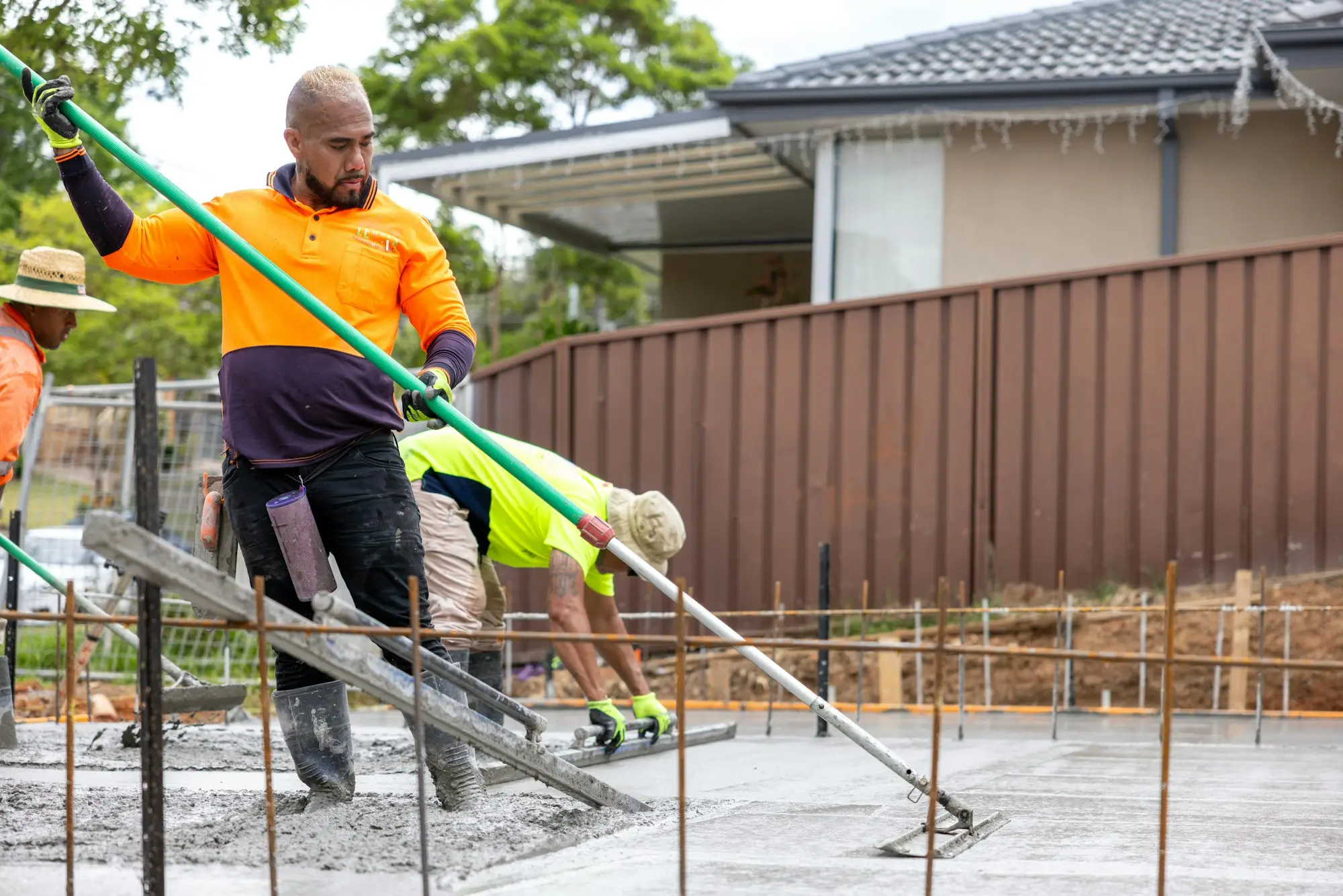 Builders smoothing a freshly poured concrete slab on a residential site in Greystanes, New South Wales