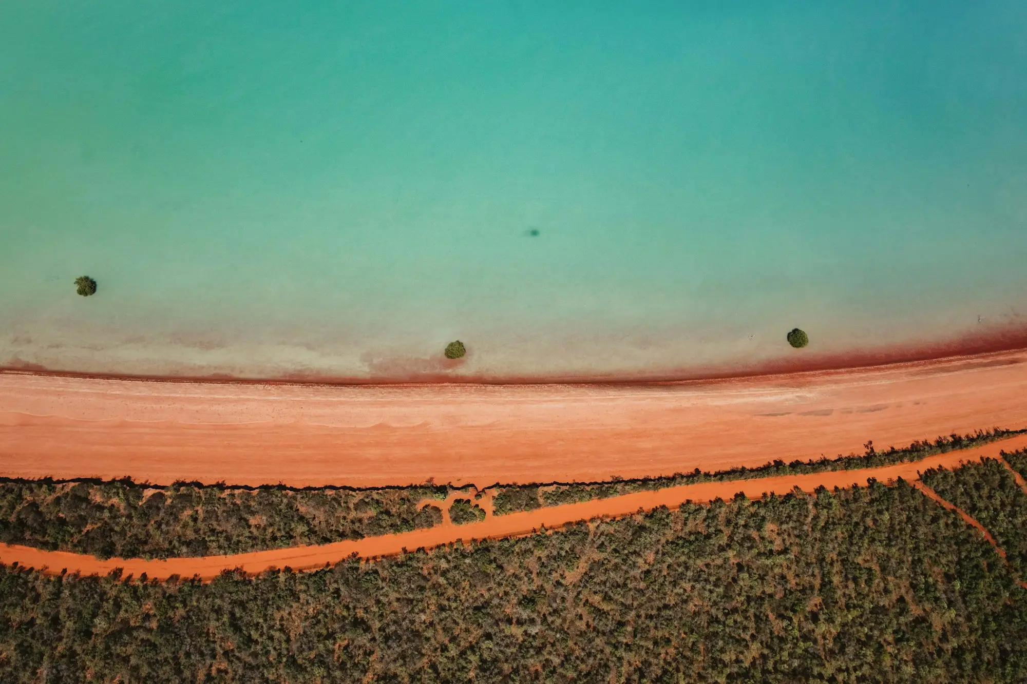 Aerial view of red earth meeting turquoise water on the Western Australian coast near Broome