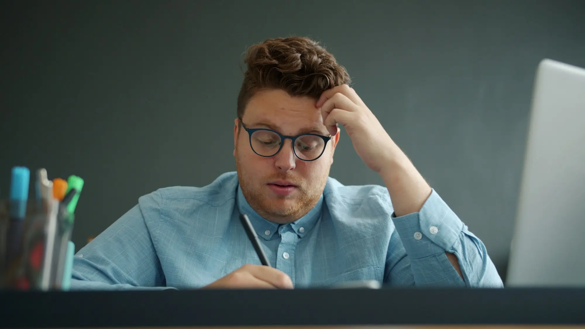 Stressed company director taking off his glasses while working through notes at his desk