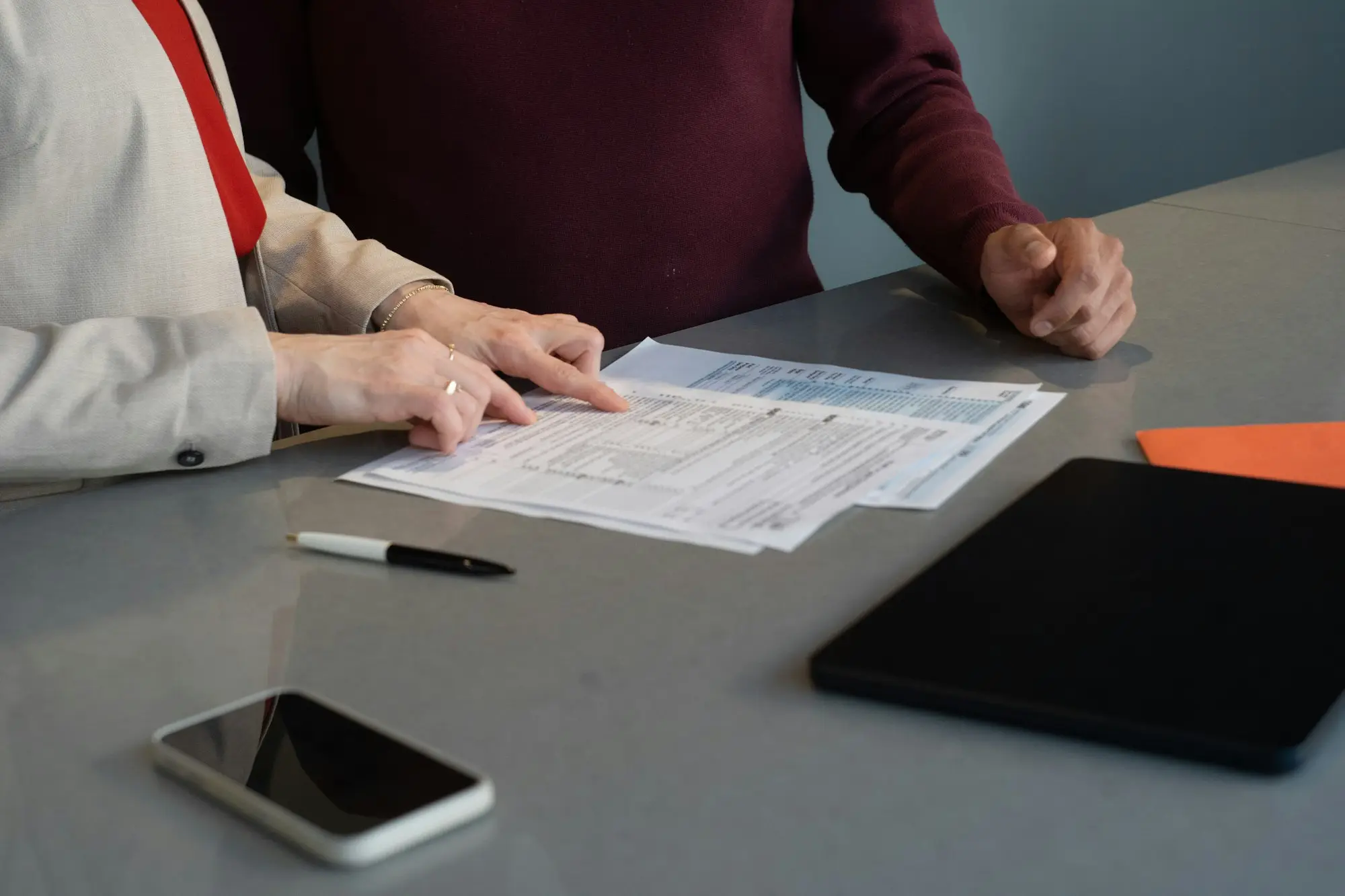 Two professionals reviewing loan paperwork together at a conference table during a business meeting