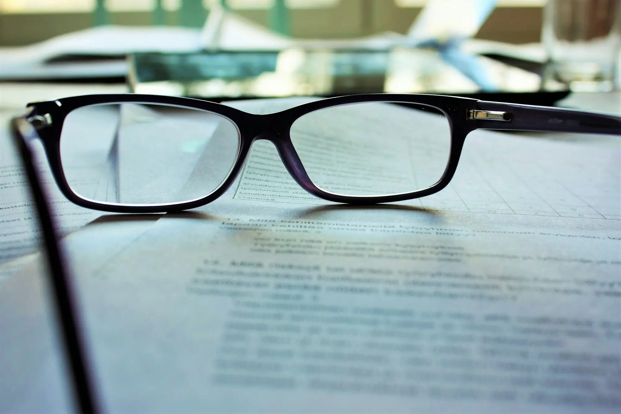 Reading glasses resting on a printed document, ready for a close review of the terms