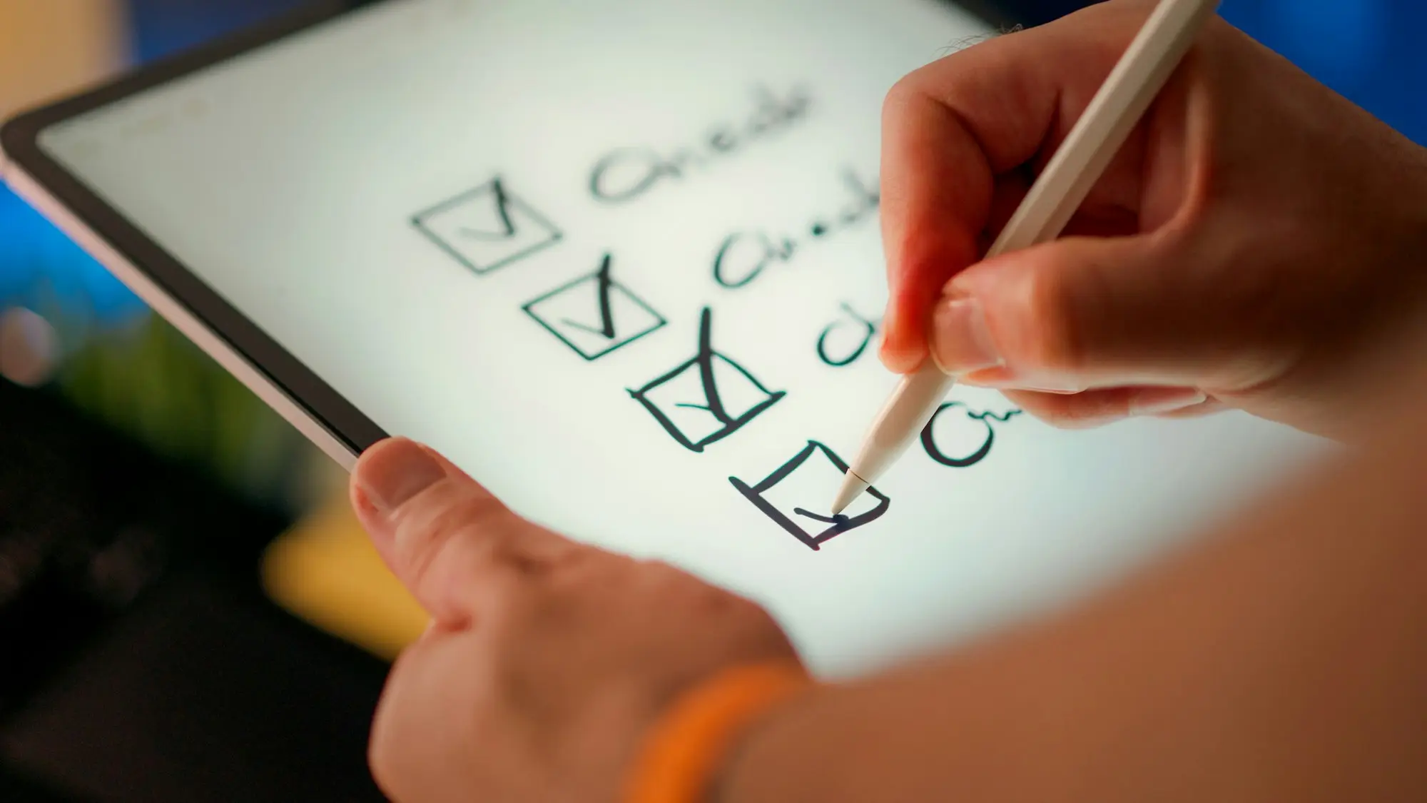Hand with a stylus ticking off items on a digital checklist on a tablet screen