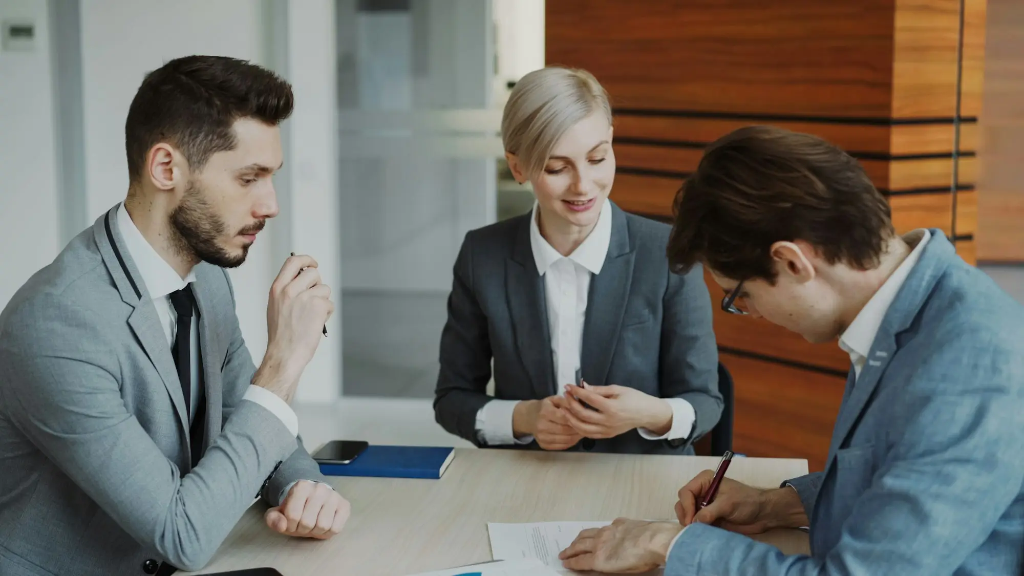 Business people signing a contract at a meeting table with a lawyer in a professional office