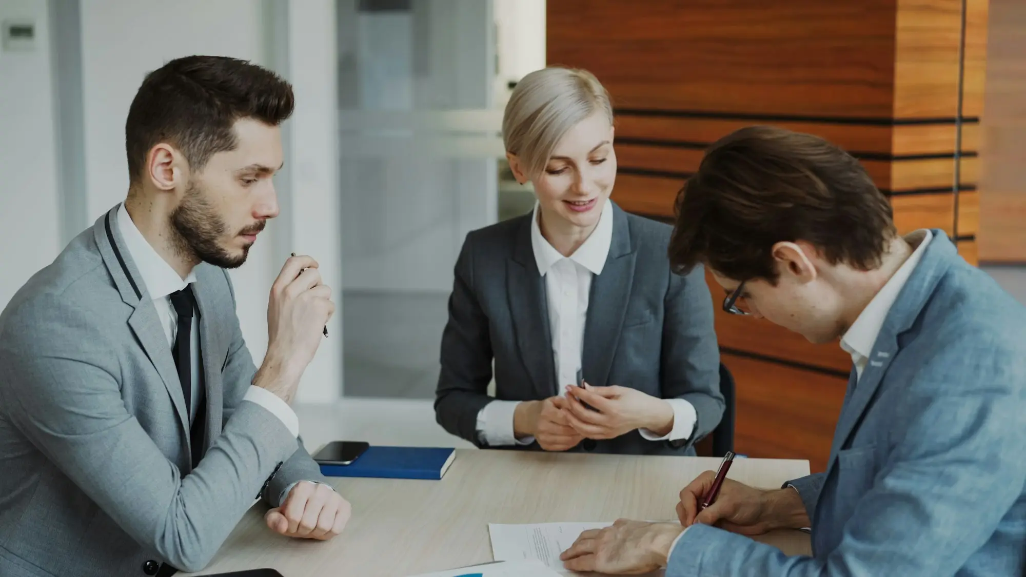 Business people signing a contract at a meeting table with a lawyer in a professional office