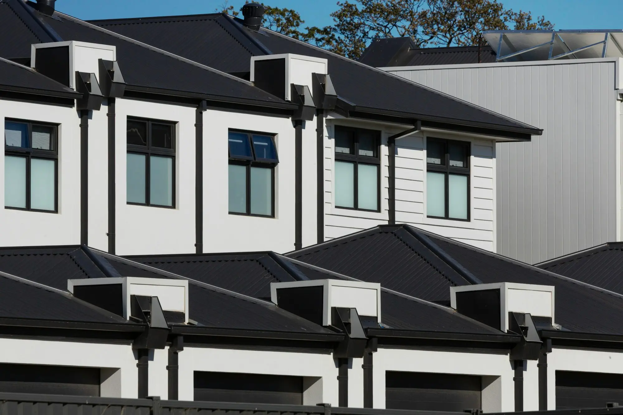 Row of new modern white houses with black roofs side by side in Beaconsfield, Victoria