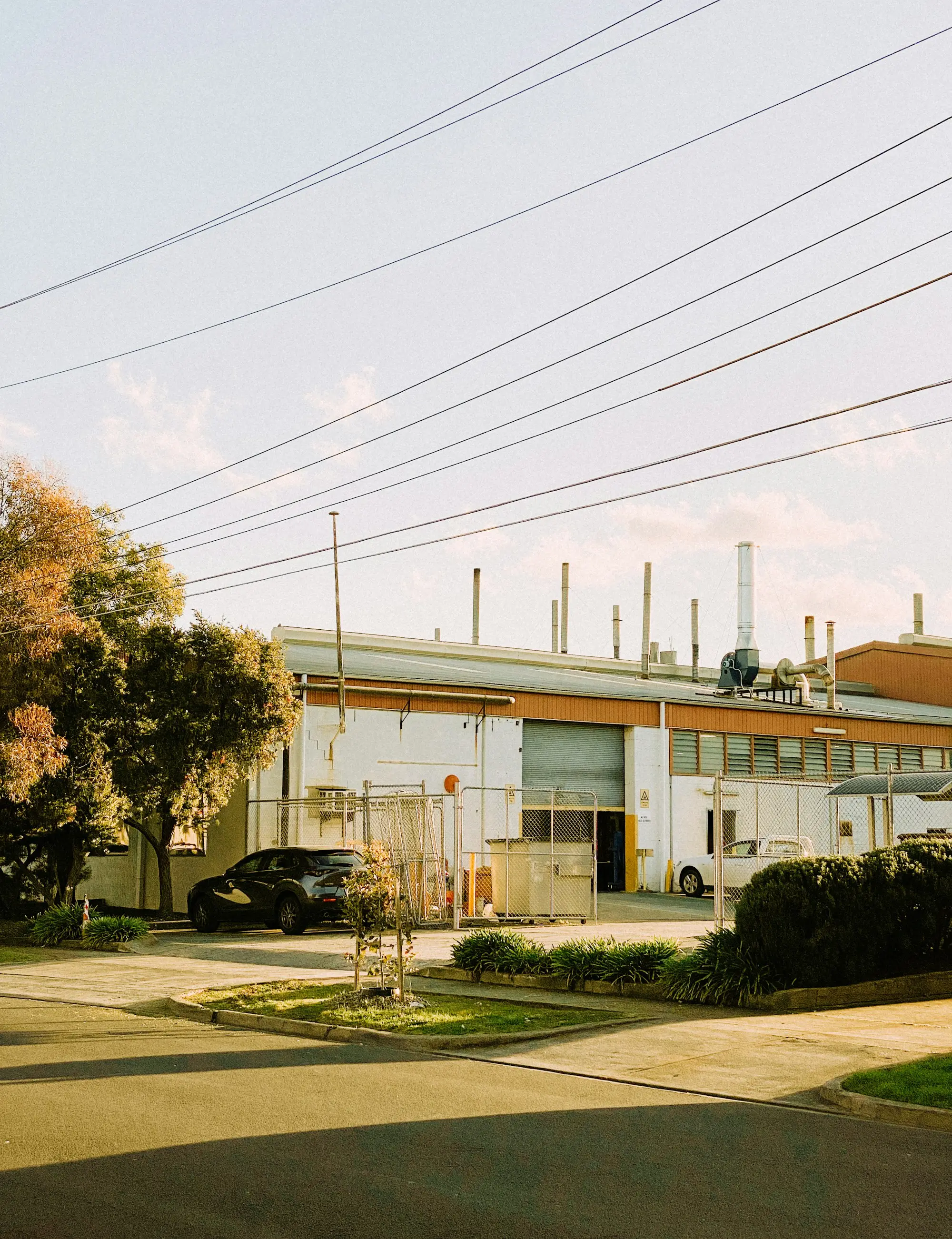 White industrial factory unit with roller door and fenced yard in Reservoir, Melbourne