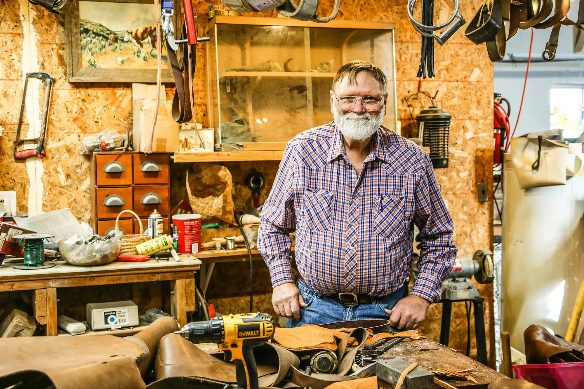 Smiling business owner in a checked shirt standing in his own workshop